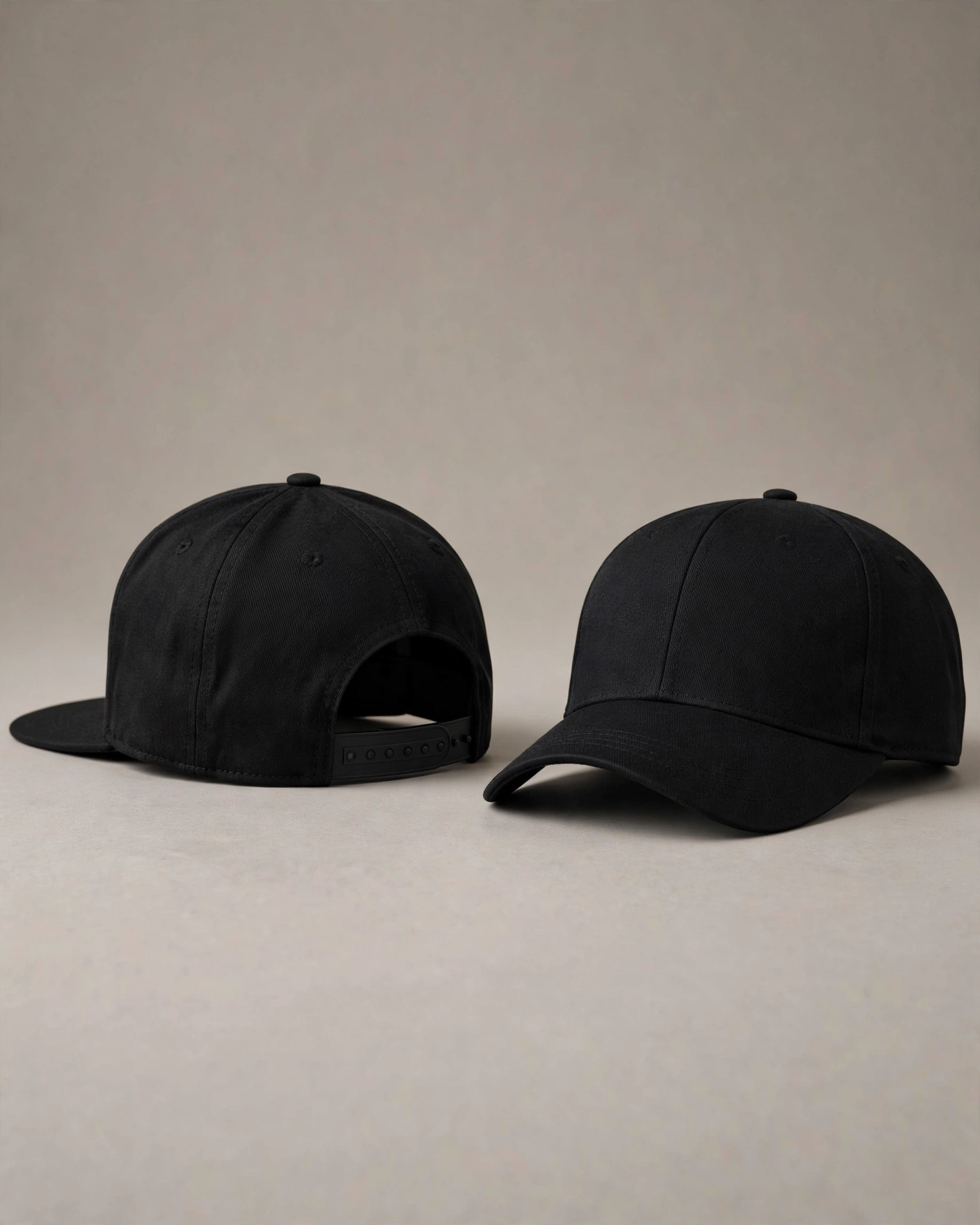 Two caps photographed side by side on a neutral background. On the left, a structured black snapback cap with a flat brim, high crown, and visible plastic snap closure at the back — shown from a three-quarter rear angle to display the closure mechanism. On the right, a fitted cap (in a dark navy color) with a curved brim, structured crown, and no closure — shown from a similar angle to emphasize the clean back panel without hardware. Both caps are photographed with soft studio lighting that highlights the texture of the cotton twill fabric and the difference in brim curvature between flat and pre-curved styles.